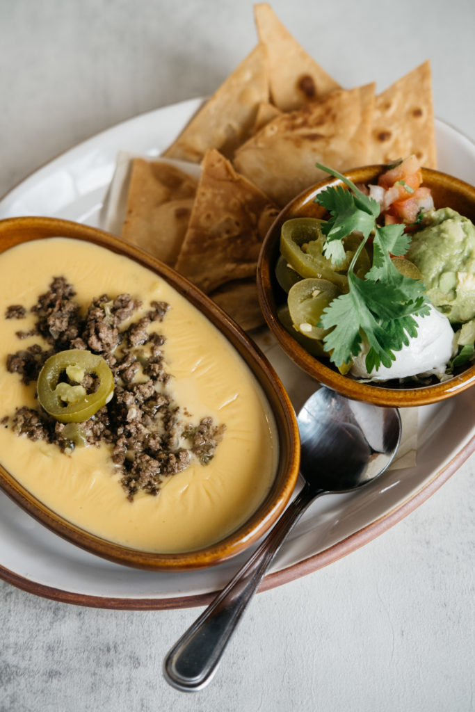 At Kitchen & Cantina, you'll find chile con queso served with ground beef, onions, and tomatoes. And topped with all the "Goode" stuff: pico de gallo, sour cream, picadillo, guacamole. (Photo by Caroline Fontenot)