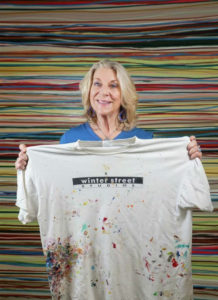 Painter Sandi Seltzer Bryant holds the T shirt that was given out to the original Winter Street Studios artists that moved into the revitalized building in 2005. (Courtesy the artist)