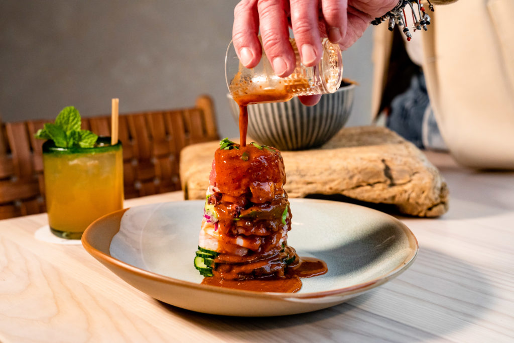 The "Ffiti Stack," short for graffiti, is composed in a clear cylinder at Graffiti Row, the new Houston restaurant. You'll spy layers of shrimp, octopus, tuna, avocado, red onion, and cucumber. The cylinder is slowly lifted off the towering display at the table, and you are offered three different condiments/sauces to flavor it. (Photo by Kirsten Gilliam)