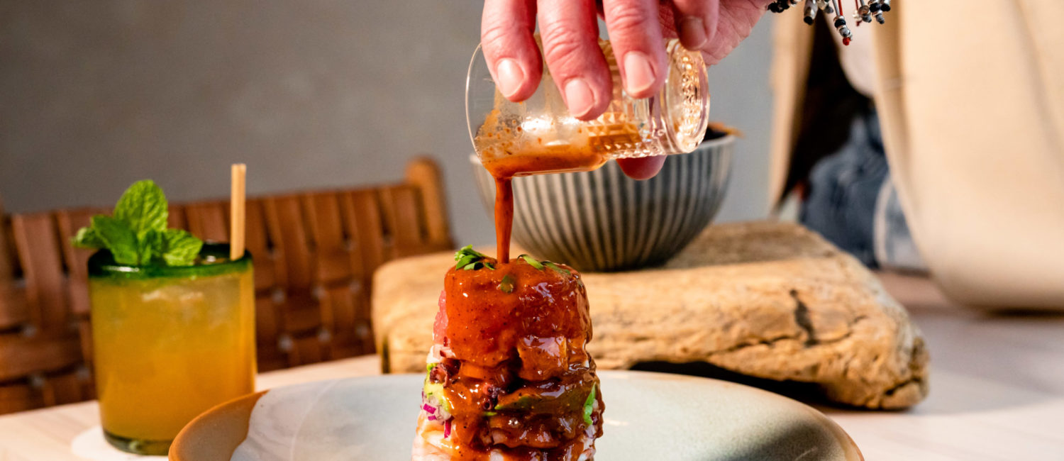 The "Ffiti Stack," short for graffiti, is composed in a clear cylinder at Graffiti Row, the new Houston restaurant. You'll spy layers of shrimp, octopus, tuna, avocado, red onion, and cucumber. The cylinder is slowly lifted off the towering display at the table, and you are offered three different condiments/sauces to flavor it. (Photo by Kirsten Gilliam)
