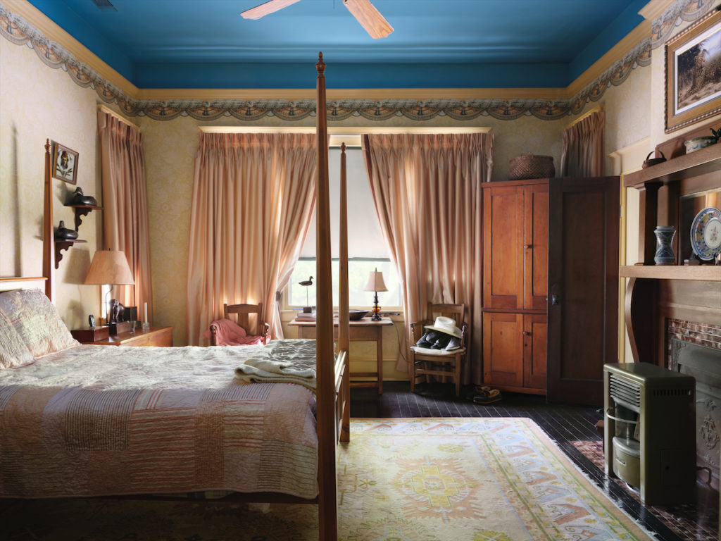 Winn Morton loved to paint ceilings celestial blue, as he did here in a bedroom. Walls and ceiling borders are fabric reminiscent of the room’s original wallpaper. (Photo by Lisa Petrole)