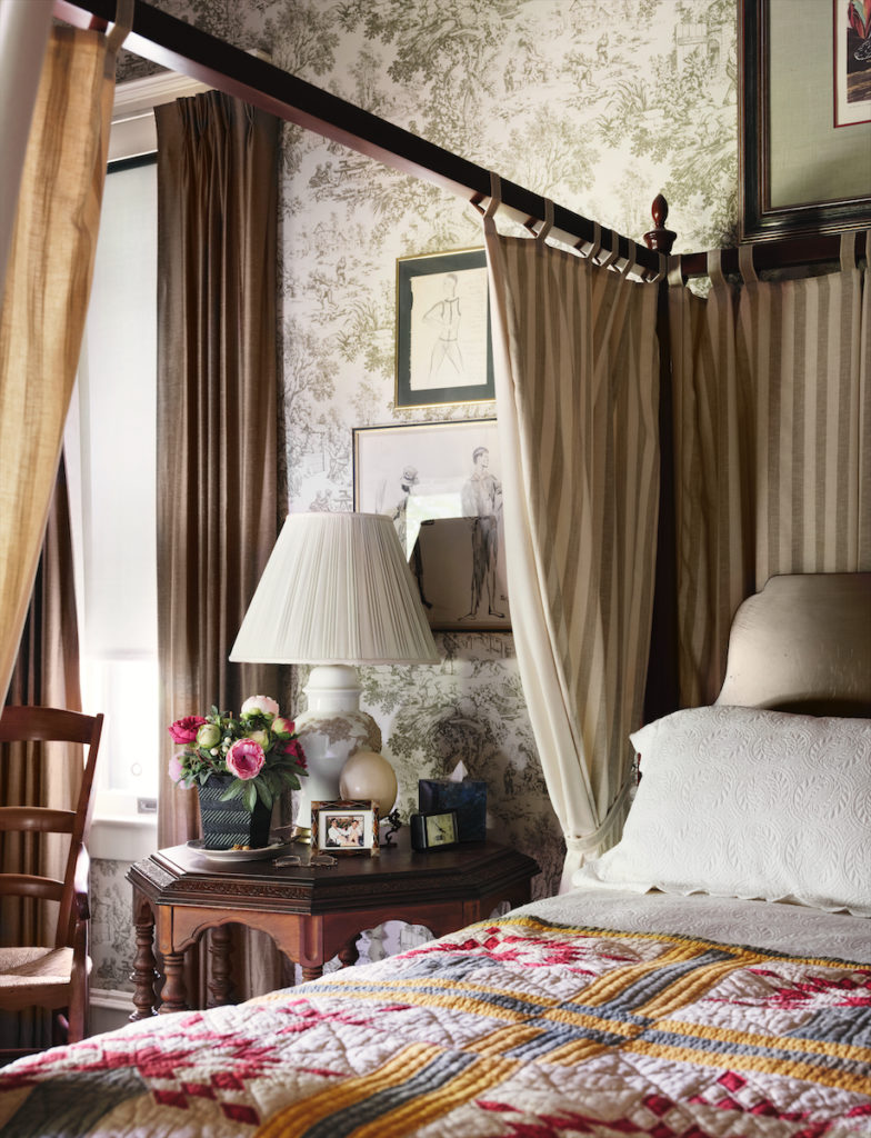 A guest bedroom is enveloped in green toile and striped fabric, added when the house was restored in the 1980s. On the wall is a Cecil Beaton drawing. (Photo by Lisa Petrole)