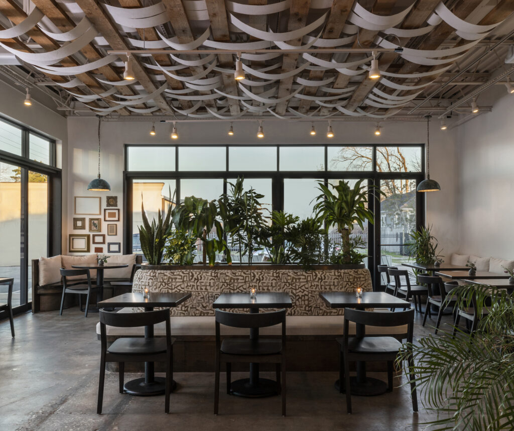 The Dining Room at Jun features a lush display of plants in the center of the seating area with an art installation created with wooden shipping pallets with strips of canvas woven between the frame. (Photo by Claudia Casbarian with JIA Media)