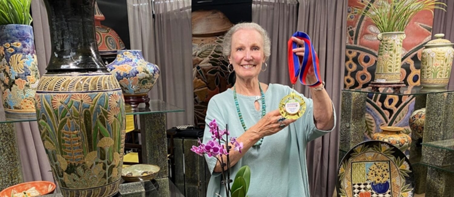 Cathra-Anne Barker shows off her Best of Show medal from the 2022 Woodlands Waterway Arts Festival.