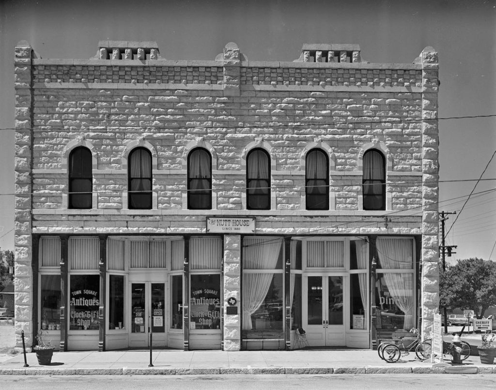 In this 1974 photo, you can see the Nutt House was being utilized as an antique store on one side and a cafe on the other, its Texas historical marker displayed prominently.