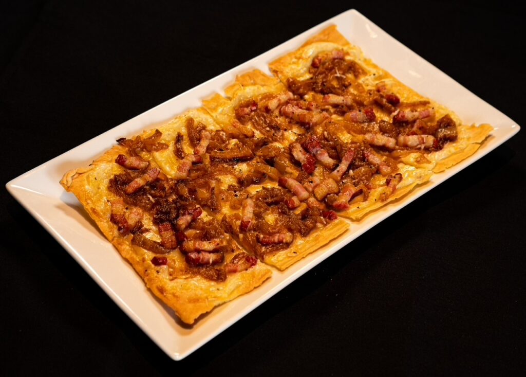 Tarte flambée l’apero ($19), the caramelized onion and bacon tart traditionally made with baker’s dough scraps and topped with crème fraiche. (Photo by Interiors: Raydon Creative, Food and Drink: Harold Cua)
