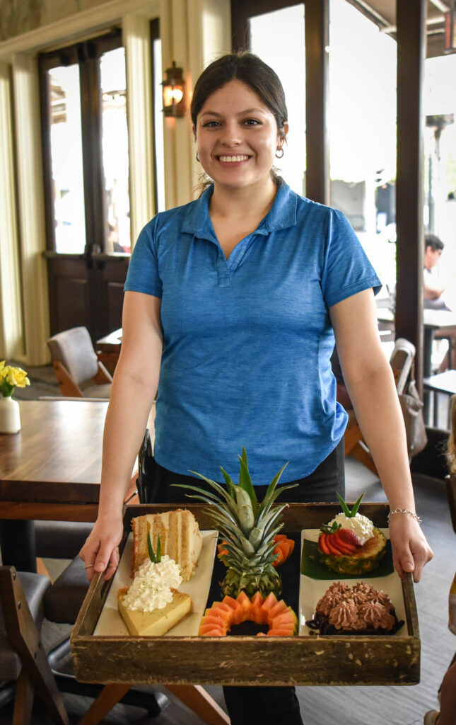 The Woodlands Tommy Bahama waitress Valery Hernandez smiles for a photo while holding the island-themed restaurant’s desert tray.