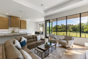 Seating and dining areas are open and share a view of the golf course at This Woodlands home.