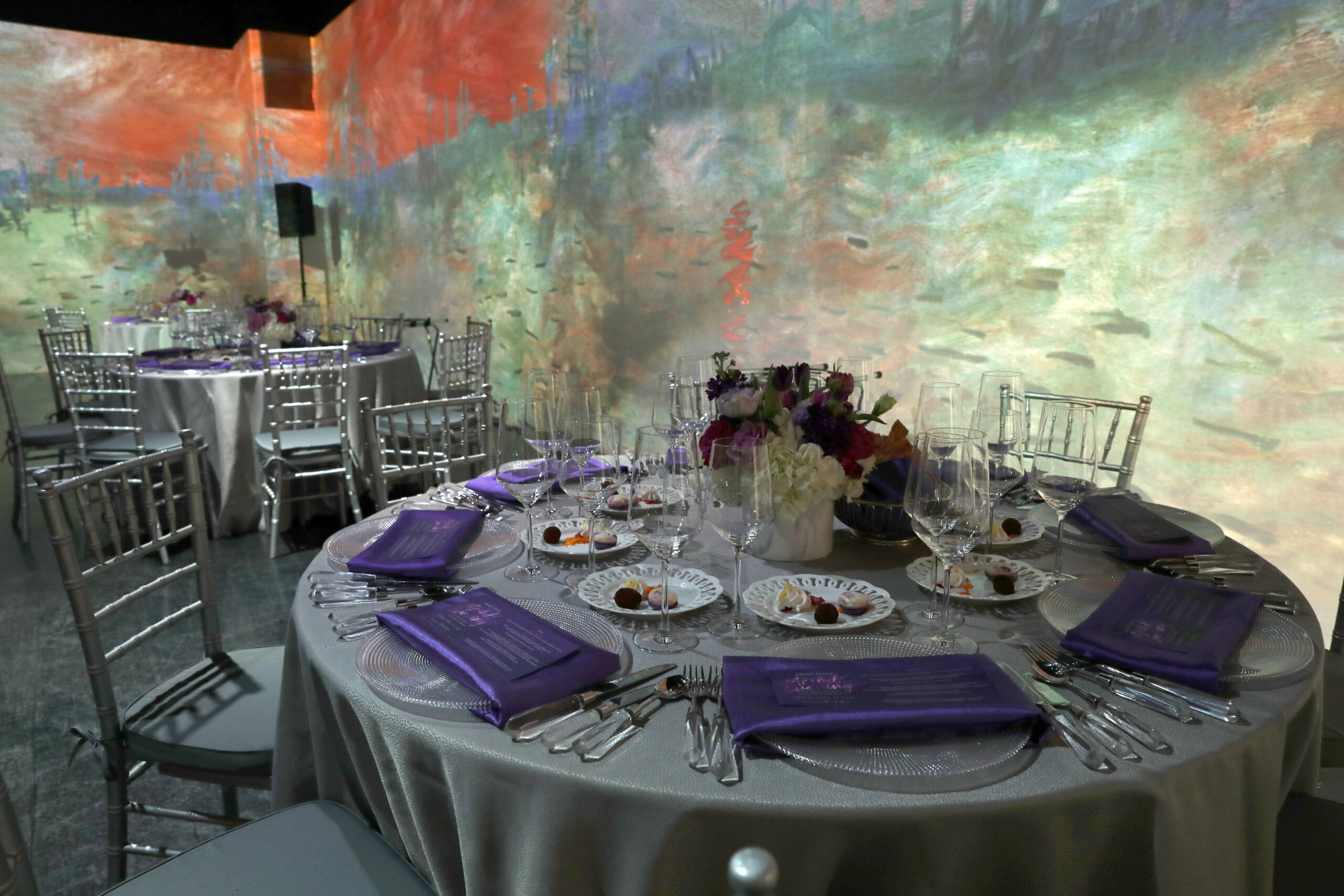 Table Setting showing the Monet and Impressionists Immersive Experience on the walls (Photo by Lisa Stewart and Rob Wythe/Wythe Portrait Studio)