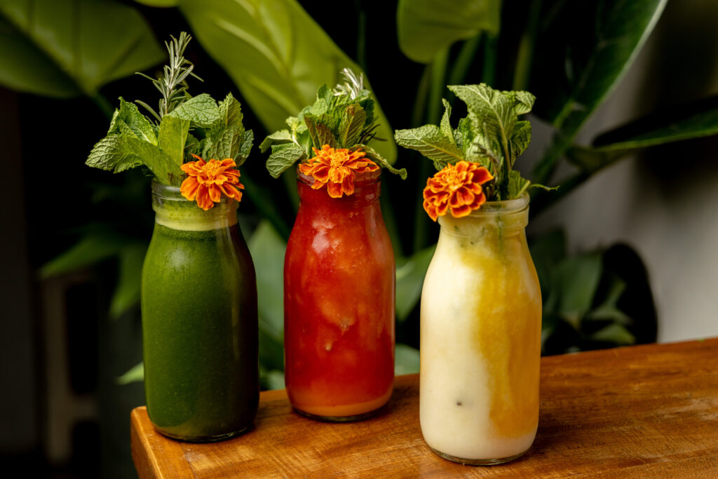 The chilled smoothies and juices at Ojo de Agua are served in glass milk jugs and topped with herbs and edible flowers. (Photo by Jennifer Hasbún)