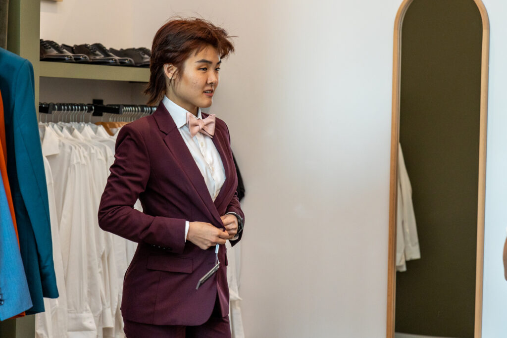 Caitlin Hsu tries on a maroon suit in the mirror. (Photo by Adam Hart)