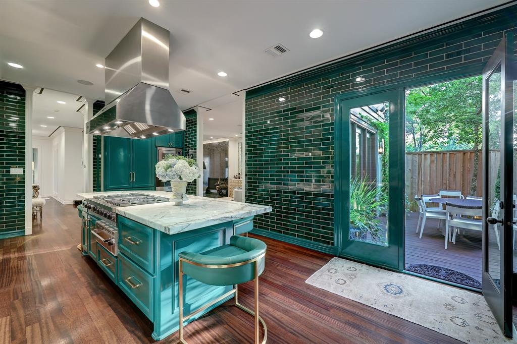 The emerald  green kitchen, despite the photo shading, in the luxurious 'Tuscan Villa' townhome at 5722 Logan Lane opens to one of two outdoor living areas. (Photo by TK Images/Compass)