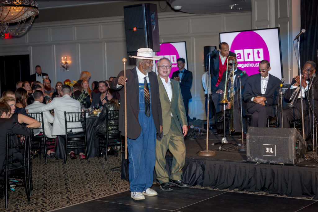 Jesse Lott is escorted to the stage by longtime friend Mel Chin, who introduced Lott, during Art League Houston's 2016 Texas Artist of the Year Gala which honored Lott with a Lifetime Achievement Award. (Photo by Alex Barber, courtesy Art League Houston)