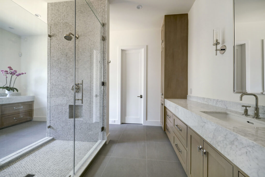 The swank primary bath features dual wings centered by the shower. (Photo by TK Images for Compass)