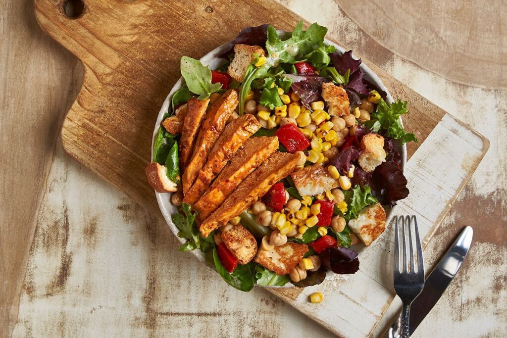 More than just grilled chicken plates, Nando's also features salads and bowls like this marinated tomato, halloumi and chicken salad. Photo by Greg Powers.