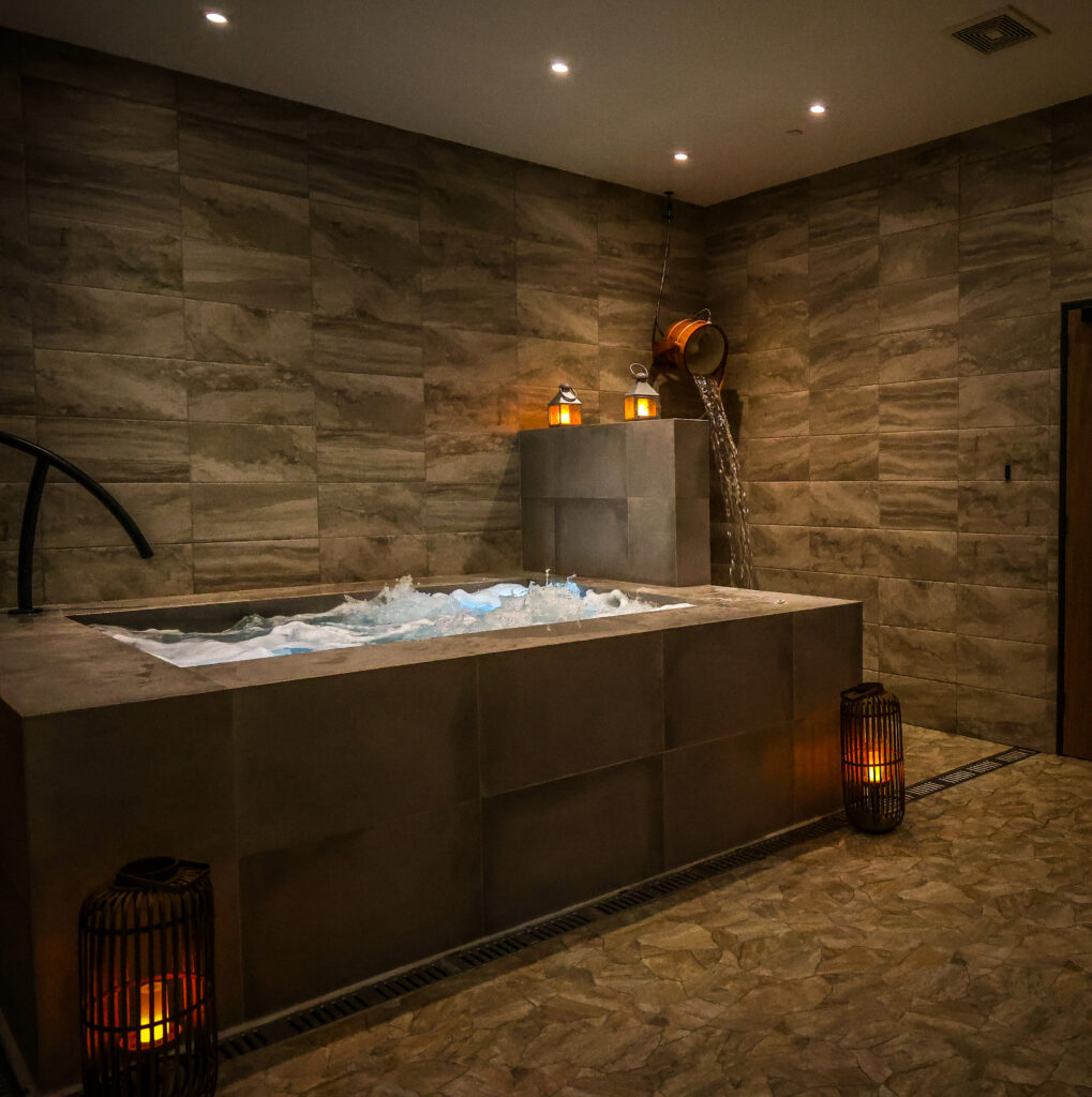 Resort-style amenities include the complimentary coed wet room. There, guests can soak and unwind those tense muscles in a bubbling 12-person hot tub, step into the eucalyptus-scented steam-filled dry sauna, then jump from hot to cold and experience a refreshing splash of contrast bathing with a simple pull of a rope. (Photo by Courtesy of Escape Spa)