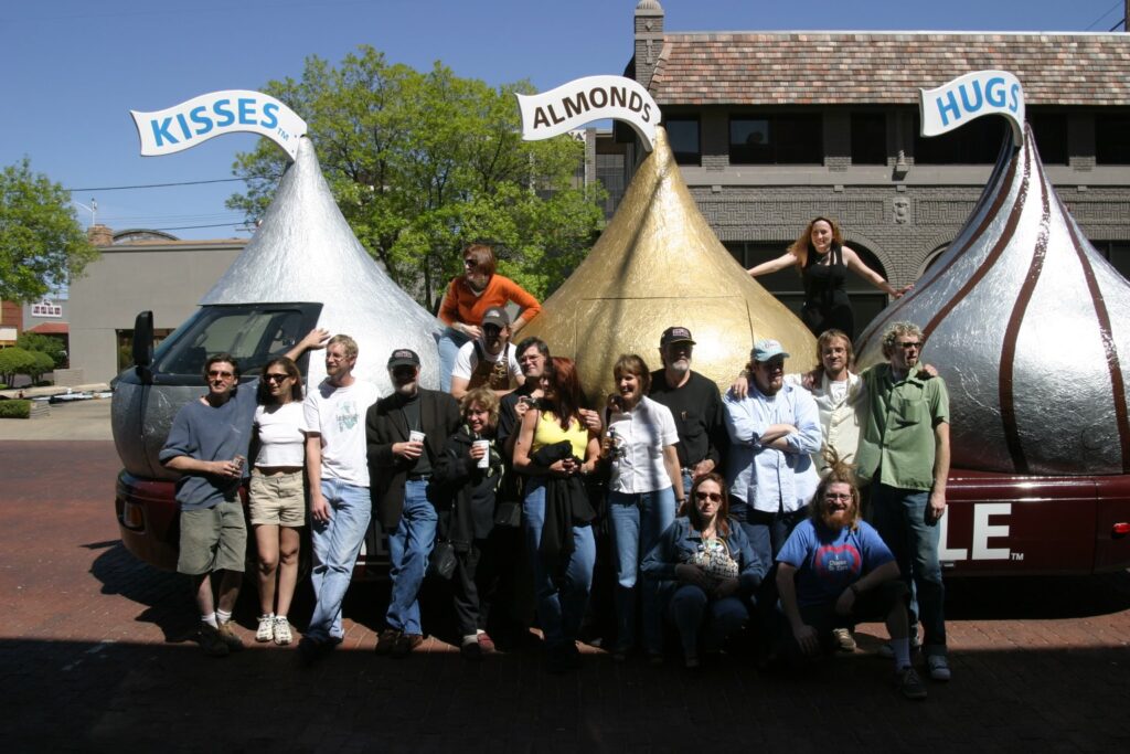 High jinx on the road: Wayne Gilbert (gold kiss with cap) and Gus Kopriva (silver kiss cab with hat) and art pals in Lubbock, Texas, with the Hershey's Kissmobile Cruiser, circa 2003.