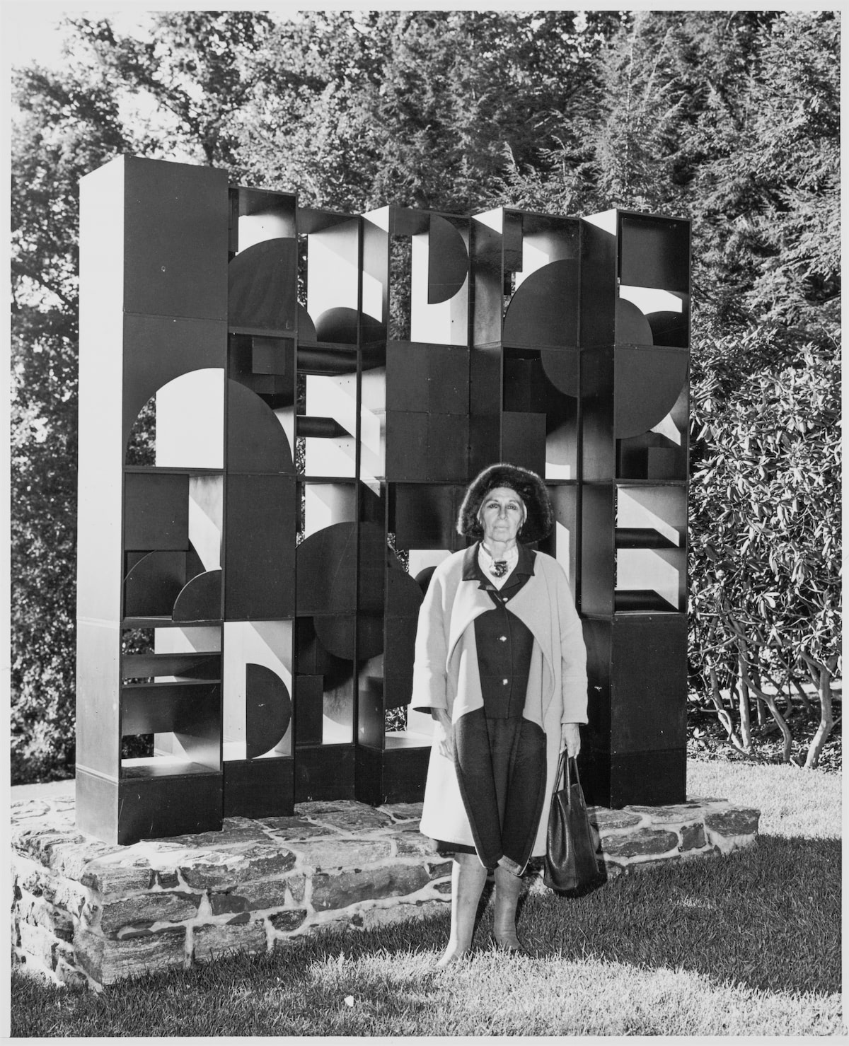 Louise Nevelson standing in front of her artwork at Pocantico Hills, 1969