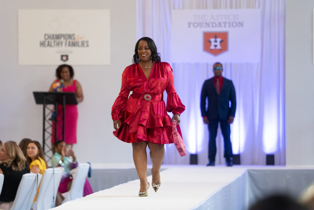 Casandra Brown models fashions from Tootsies at the Astros' 'Champions for Healthy Families' luncheon at Union Station as hubby Dana Brown, Astros GM, watches from the back. (Photo by Daniel Ortiz)