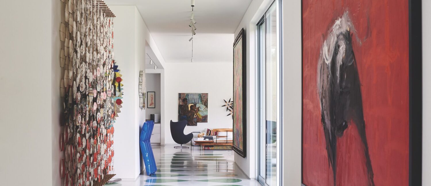 The front hallway’s custom terrazzo floors, laid by National Terrazzo Tile & Marble, were inspired by the Havana Riviera in Cuba. Right, red painting by Tonio Trzebinski. Left, Jacob Hashimoto’s kites. Metal pool float sculpture by Will Cannings. Vintage egg chair. Painting by Inga Kimberly Brown. Small orange boot lithograph by Andy Warhol. (Photo by Pär Bengtsson)