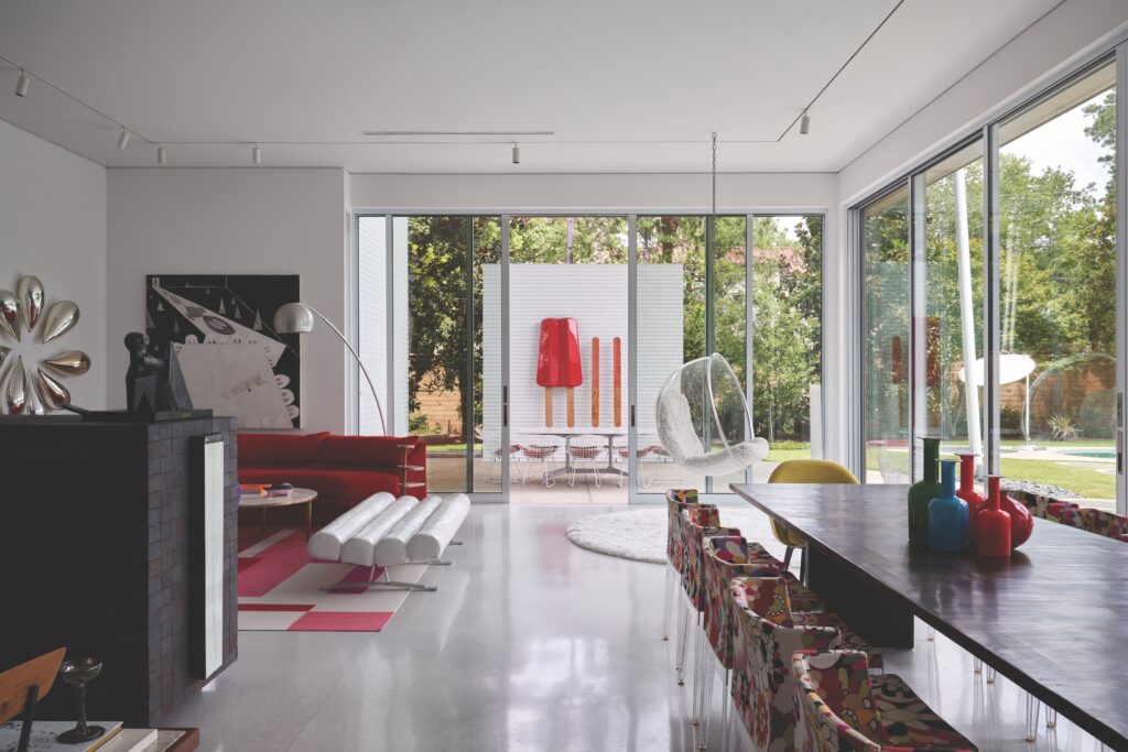 A dining and seating area with black bamboo dining table from Wyeth and Philippe Starck chairs in Missoni fabric. Eero Aarnio Bubble pendant chair and vintage white patent-leather tube bench from London. Custom rug by Vanderhurd. Painting on fireplace by Gabriela Trzebinski, sculpture by Luis Ortiz Monasterio. On wall outside, Tim Berg and Rebekah Myers’ Twin Pop sculpture. (Photo by Pär Bengtsson)