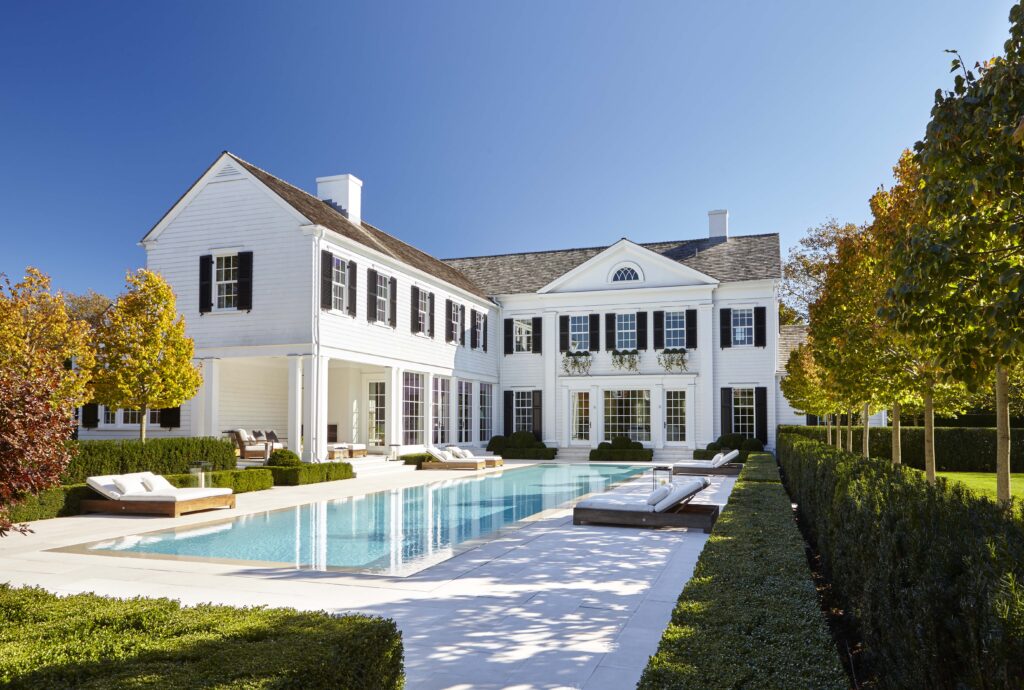 The garden façades of a Southampton house designed by Sawyer | Berson, overlook the swimming pool terrace, which is framed by clipped boxwood, yews, and linden trees. (Photo by Joshua McHugh) 