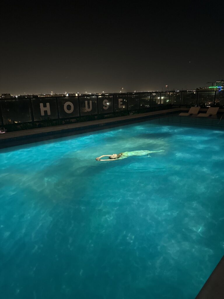 A swimmer floats in the water alongside a projection of herself at the "Surface Tension" reception. (Photo by Haley Berkman Karren) 