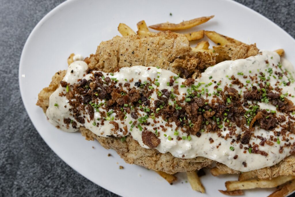 The Rub's nightly chicken fried steak —currently on the Memorial Green location's  lunch menu is made with the
ribeye cut topped with bacon studded white gravy and French fries. (Photo by Lauren Holub )