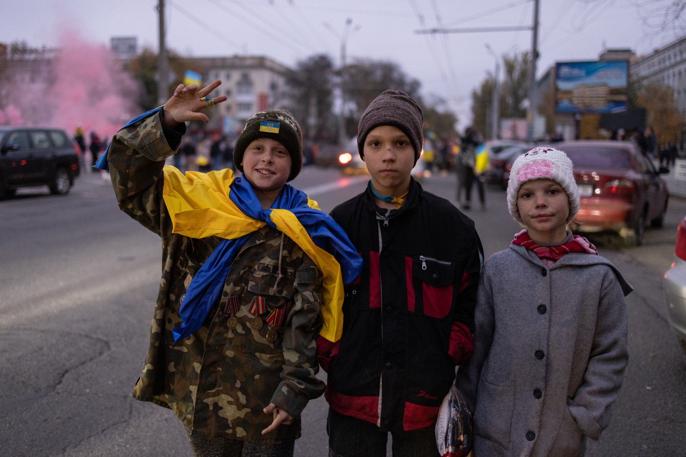 Children with a Ukrainian flag and uniforms flash the victory sign on the central square of Kherson during celebrations of the city’s liberation by Ukrainian army. November 12, 2022.(Photo by Andriy Dubchak. Courtesy Ukrainian Association of Professional Photographers)