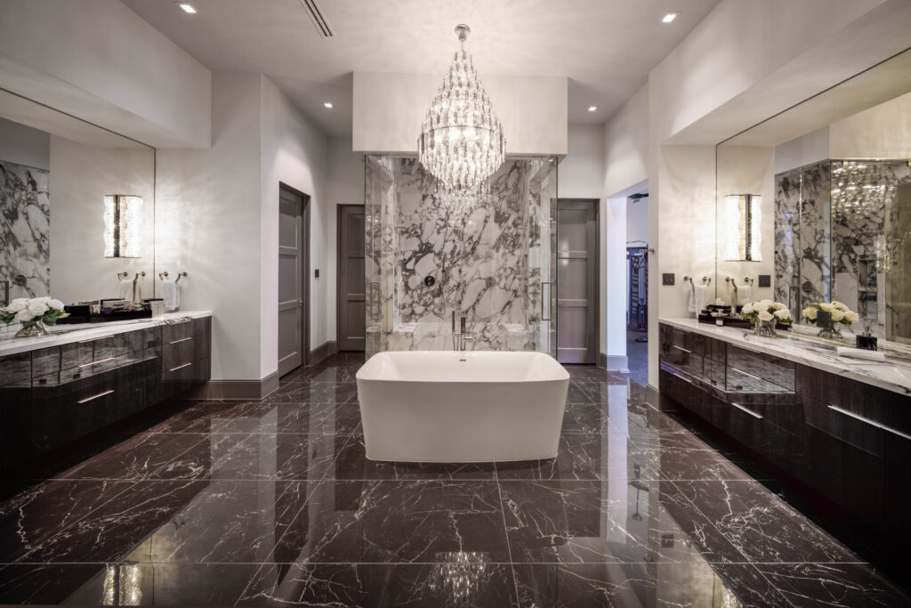 An impressive luxury primary bathroom is every owner's dream. Focal points of this magnificent space are the dual vanities with porcelain countertops and floors, modern crystal wall pendants and a custom chandelier with clarity crystals. (Photo by Steve Chenn)