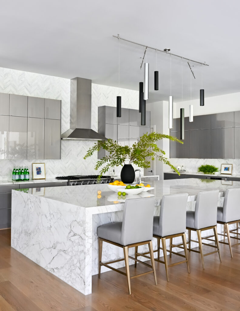 The kitchen at this Carlton Woods mansion has comfortable island seating, with sleek cabinets and contemporary lighting.