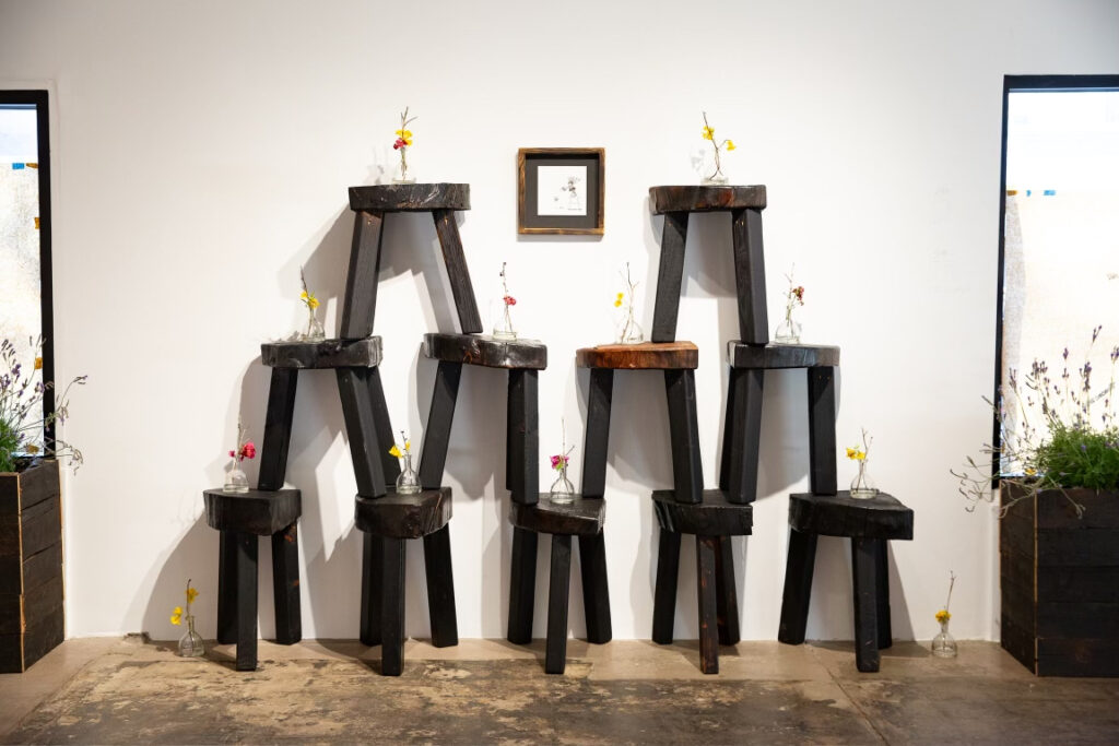 Mr. Tomonoshi's "Watering Day" next to Yakisugi stools featuring Ikebana arrangements, 2023, at Reeves Art + Design  (Photo by Jessica Dao)