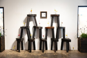 Mr. Tomonoshi's "Watering Day" next to Yakisugi stools featuring Ikebana arrangements, 2023, at Reeves Art + Design (Photo by Jessica Dao)