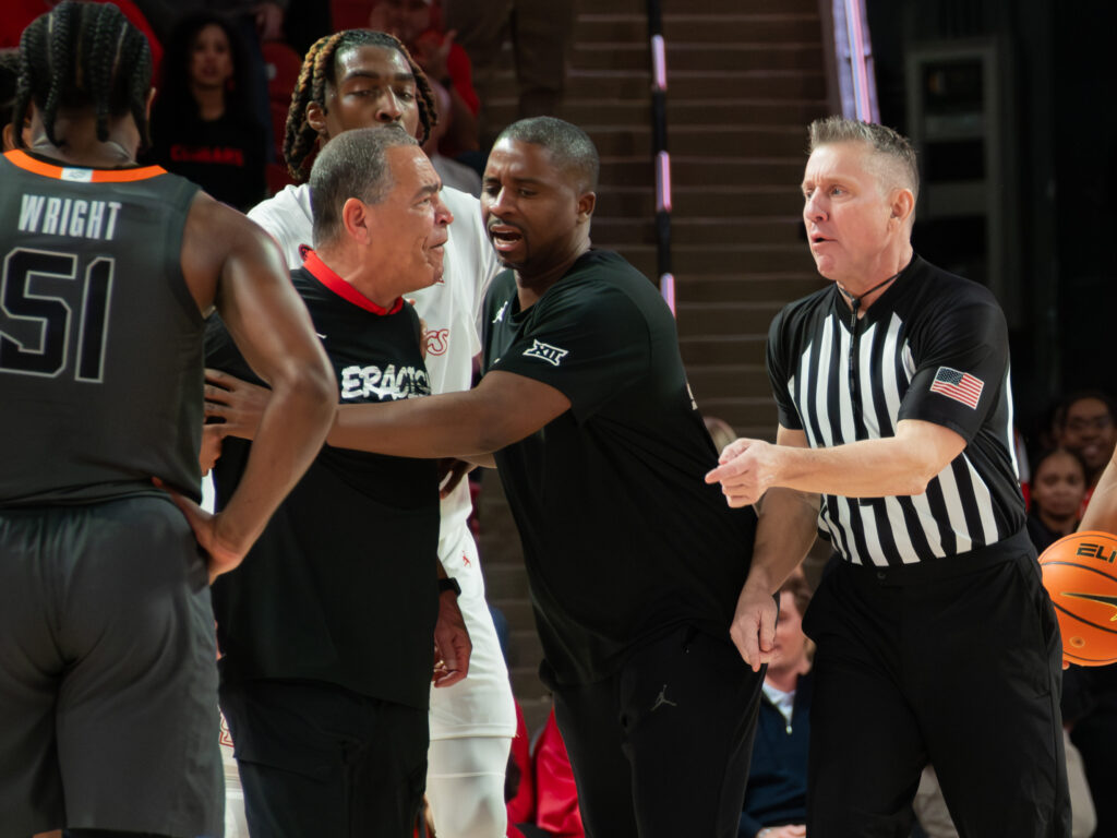 Houston associate head coach Quannas White kept Kelvin Sampson from getting too close to the officials. (Photo by F. Carter Smith)