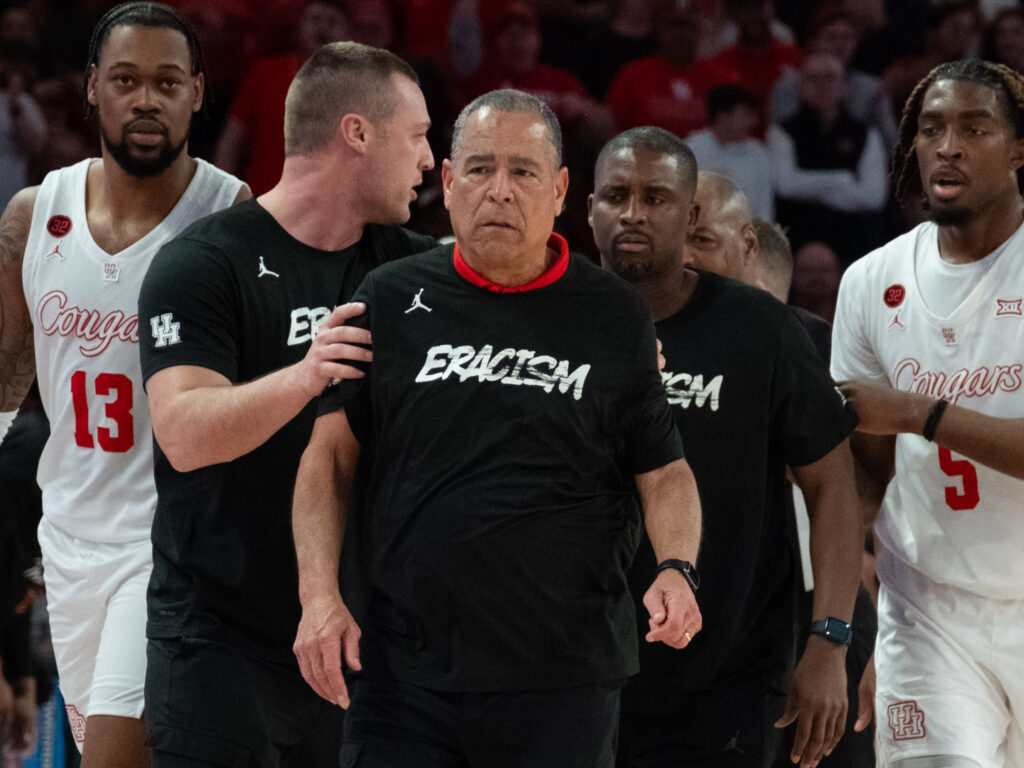 Alan Bishop (left) and Quannas White (right) helped get UH coach Kelvin Sampson into the locker room. (Photo by F. Carter Smith)