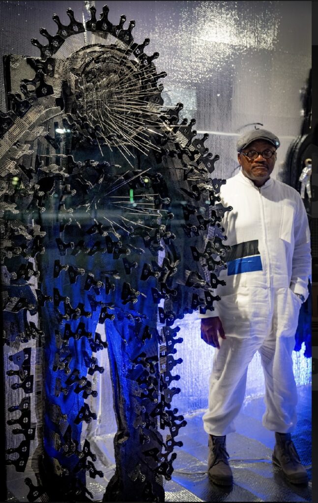 Artist Christopher Blay stands next to his Diaspronaut figure inside his Ion Building installation, called "The SpLaVCe Program."