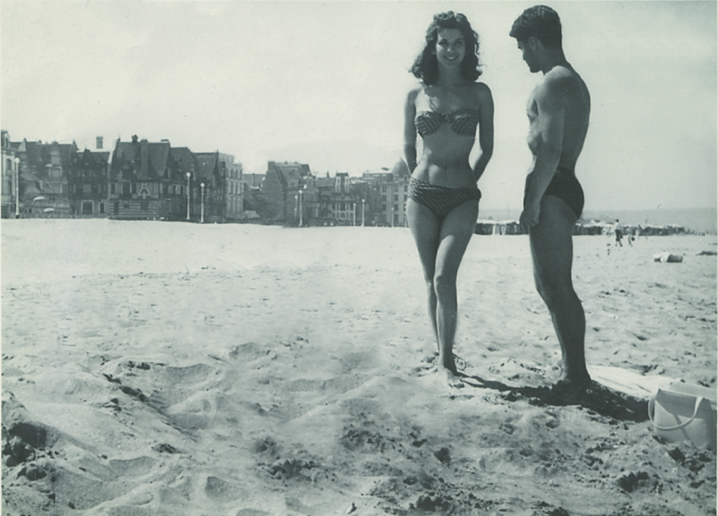In the summer of 1956, Karl Lagerfeld at the beach in Deauville with model Victoire Doutreleau—in the original, sitting on the sand on the left, was a young Yves Saint Laurent, who Karl had banished from the photo. (Courtesy William Middleton)