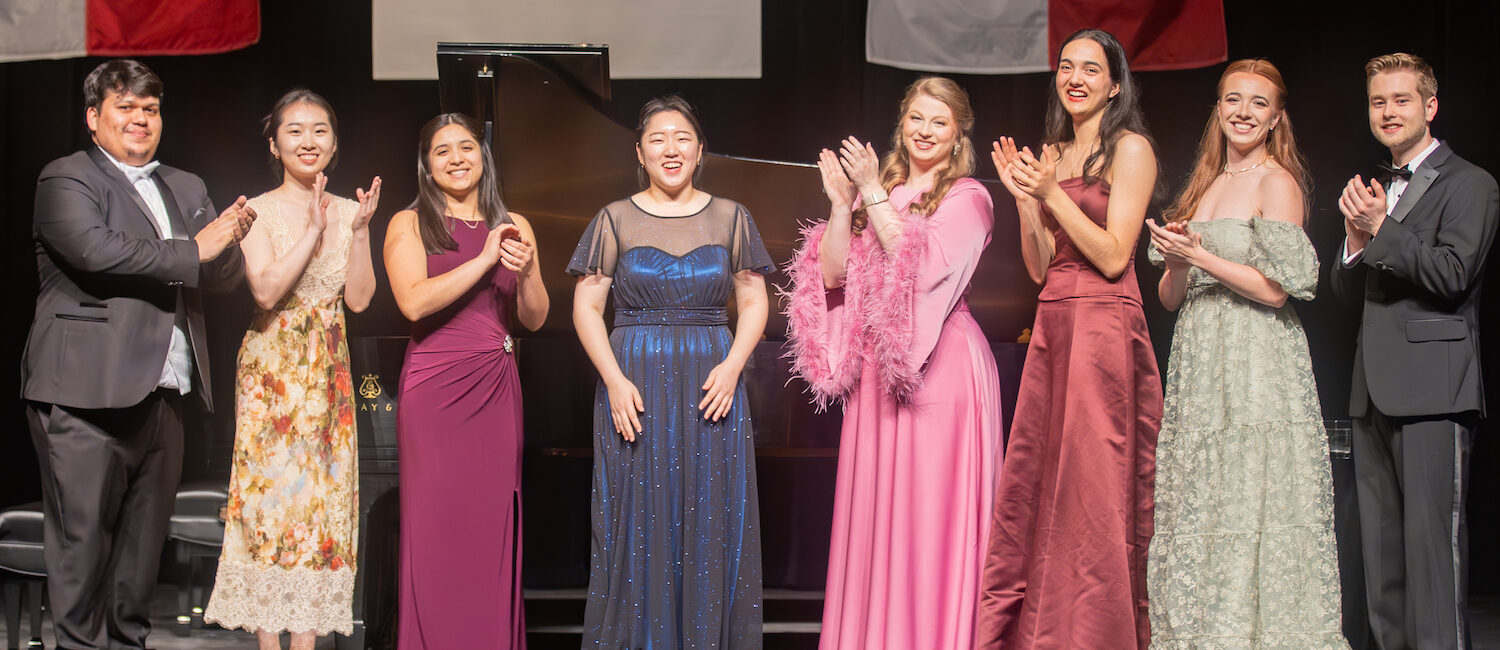 Young Texas Artists Music Competition finalists applaud Daeun Han, Grand Prize Winner and Gold Medalist in Piano (center, blue dress). Also shown, from left to right, are tuba player Roberto Gaitan, Silver Medalist in the Winds, Brass, Percussion, Harp and Guitar division; Xin Cui, Silver Medalist in Piano; saxophonist Rachel Jimenez, Gold Medalist in Winds, Brass, Percussion, Harp and Guitar and the Audience Choice Award winner; soprano Krista Renée Pape, Gold Medalist in the Voice division; cellist Claire Druffner, Silver Medalist in Strings; mezzo-soprano Joanne Evans, Silver Medalist in Voice; and cellist Maximus Gurath, Gold Medalist in Strings. (Photo by Dave Clements)