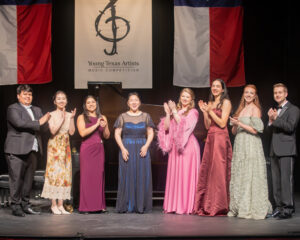 Young Texas Artists Music Competition finalists applaud Daeun Han, Grand Prize Winner and Gold Medalist in Piano (center, blue dress). Also shown, from left to right, are tuba player Roberto Gaitan, Silver Medalist in the Winds, Brass, Percussion, Harp and Guitar division; Xin Cui, Silver Medalist in Piano; saxophonist Rachel Jimenez, Gold Medalist in Winds, Brass, Percussion, Harp and Guitar and the Audience Choice Award winner; soprano Krista Renée Pape, Gold Medalist in the Voice division; cellist Claire Druffner, Silver Medalist in Strings; mezzo-soprano Joanne Evans, Silver Medalist in Voice; and cellist Maximus Gurath, Gold Medalist in Strings. (Photo by Dave Clements)