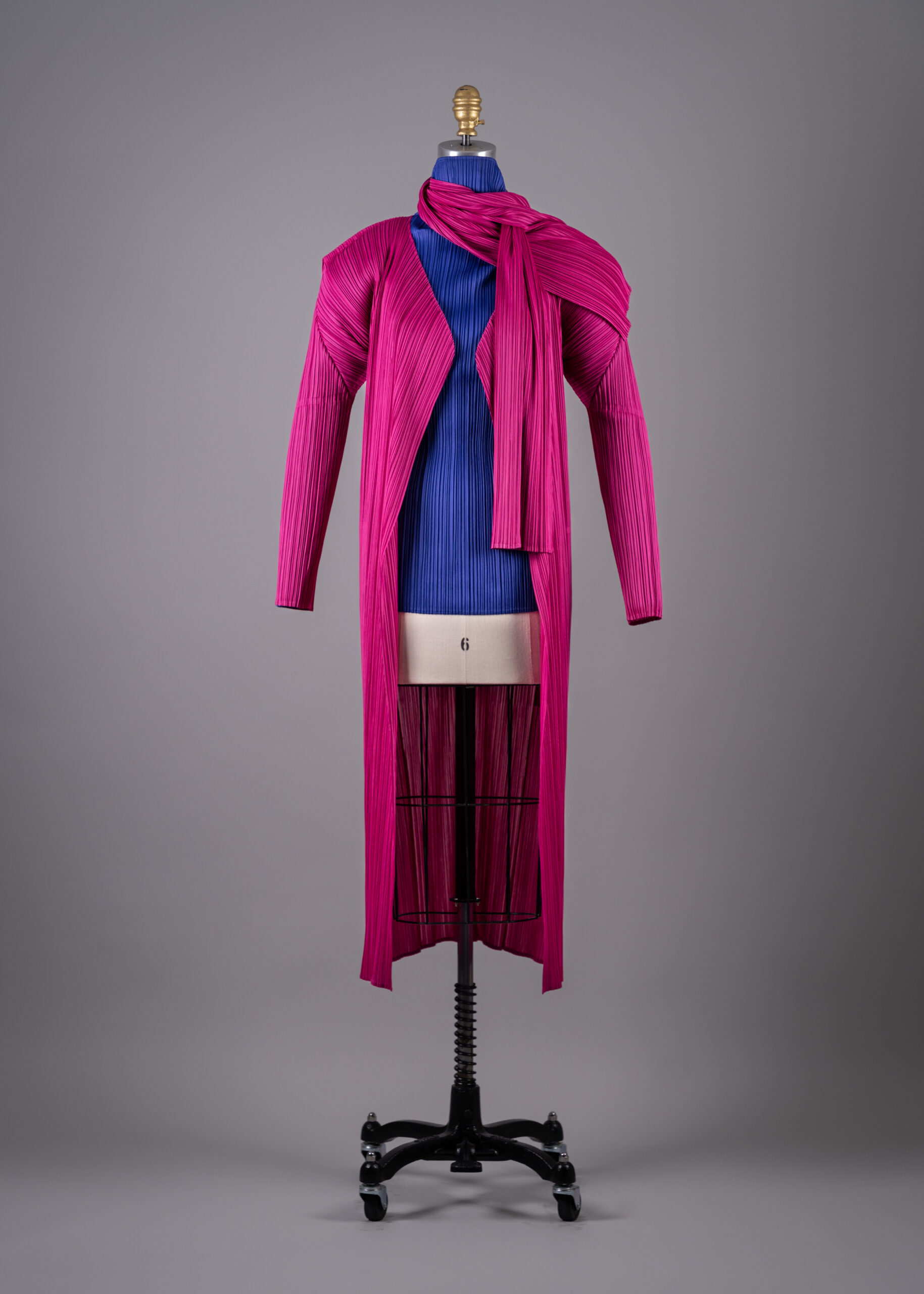 Issey Miyake's violet-blue polyester pleated turtleneck top with pink polyester pleated coat and scarf (Photo by Shane Quereshi)