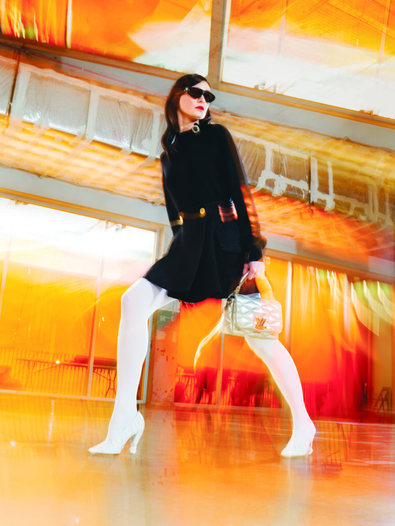 Louis Vuitton jewel-button pullover $1,640, button-front-box-pleat-mini skirt $3,300, Touch of LV tights $435, LV knot pump $1,360, GO-14 MM handbag $6,750, and LV split cat-eye sunglasses $555. 