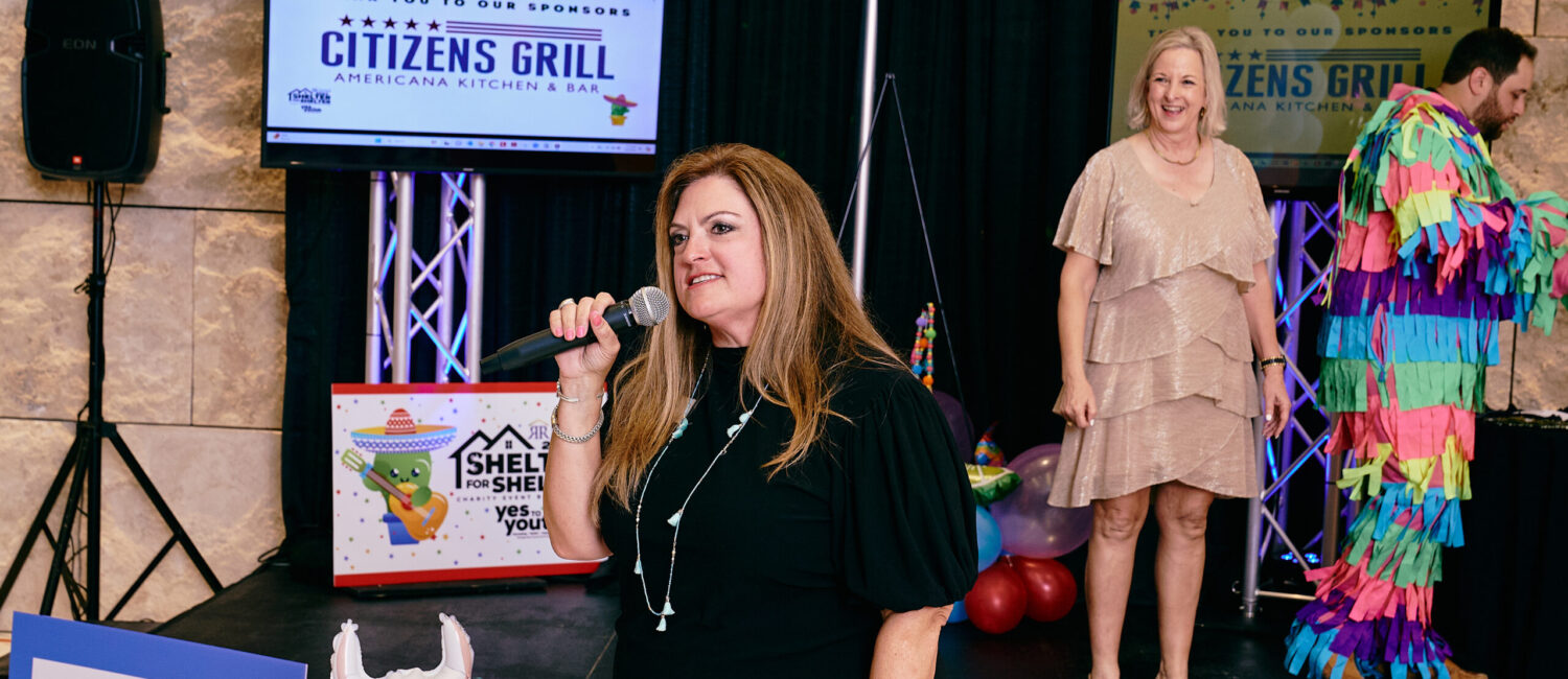 Michele Kooken, CEO of YES to YOUTH, addresses the crowd as Marlys Mulkey looks on.