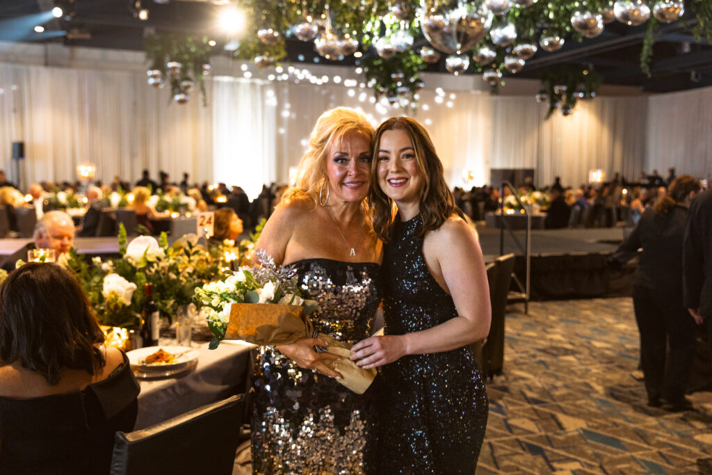 Rachel Ray, TWCA’s director of development, presents thank you flowers to 2024 Auction & gala chair Amanda Gaige. (Photo by Kyle Rogers)