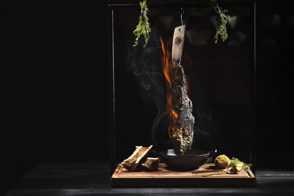 The night I dined at Toca Madera, a neighboring table of four gentlemen ordered the Flintstone-size 40-ounce flaming tomahawk ($325) the mighty cut was wheeled to their table ablaze, dangling from a hook, the flames licking the massive bone-in cut.