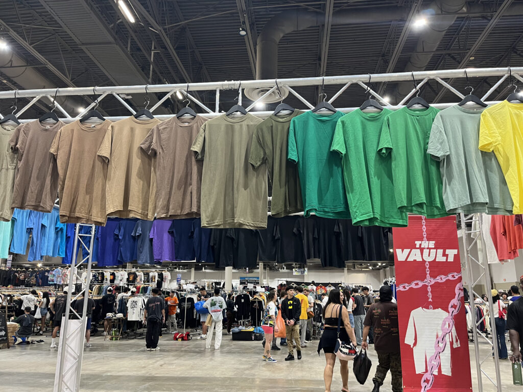 T-shirts of a gradient from grey to light blue hang above attendees heads (Photo by Jenna Baer)