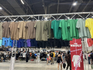 T-shirts of a gradient from grey to light blue hang above attendees heads (Photo by Jenna Baer)