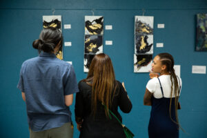 Three art enthusiasts discuss Pooja Taneja's fluid "Dance of Life" series (Photo by Derik J. Mercado)