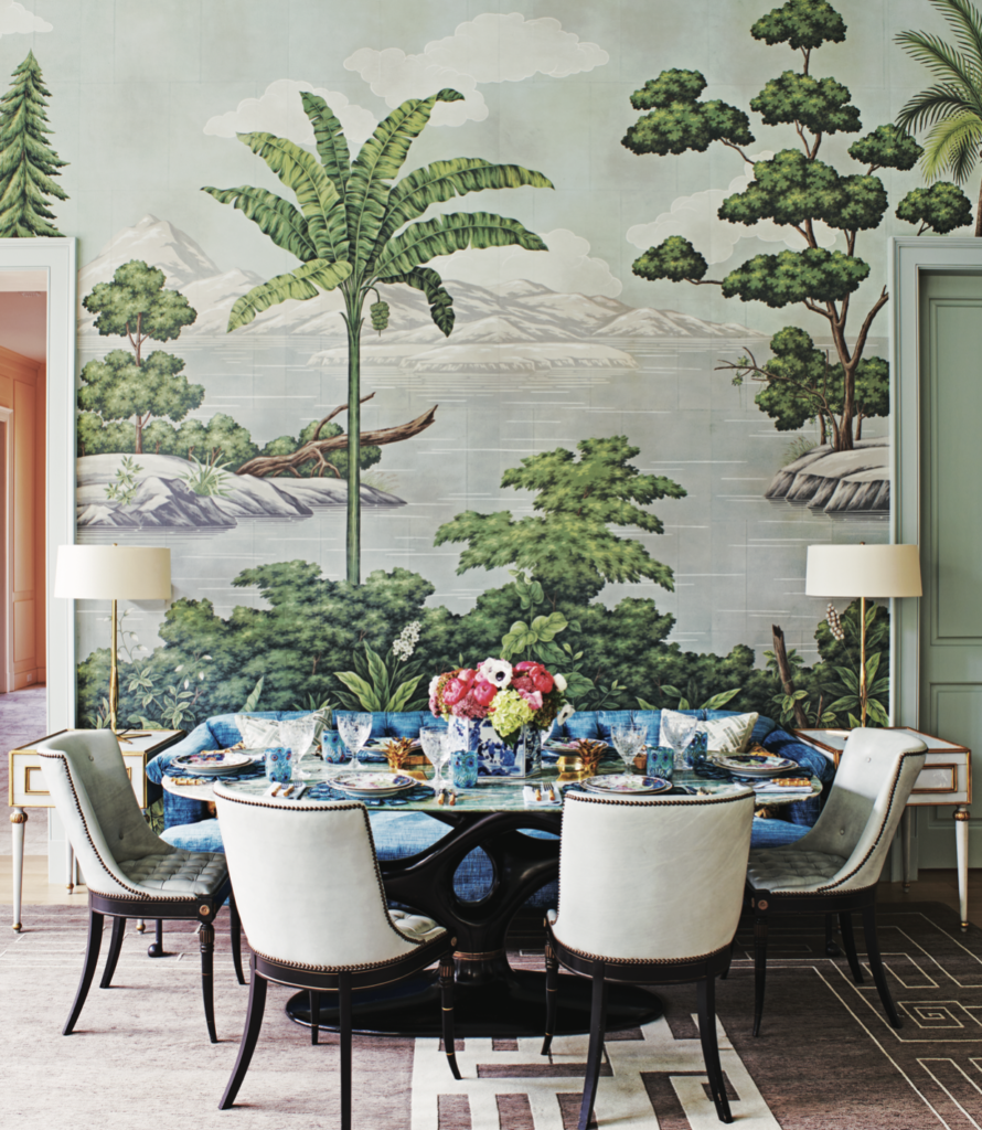 A dining area in the living room with Gracie’s New World panoramic landscape wallpaper and chairs in the style of Maison Jansen from Muse on Slocum. Italian glass side tables from Nick Brock Antiques. Custom BDDW sofa. Dining table from Balsamo, NY. (Photo by Richard Powers)