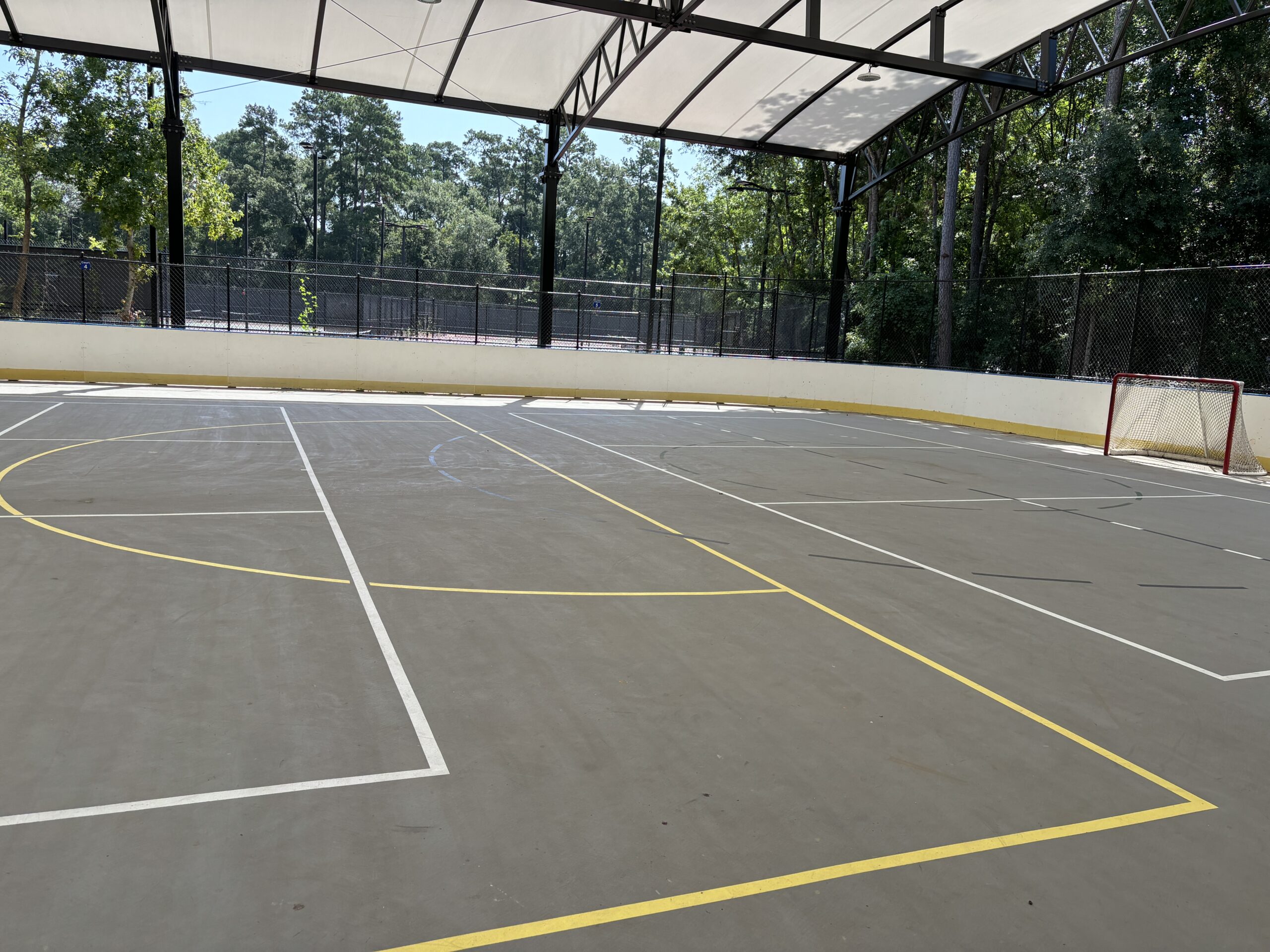 Permanent yellow lines mark the surface of the new multi-use court for netball in The Woodlands. Pickleball court lines are in white.