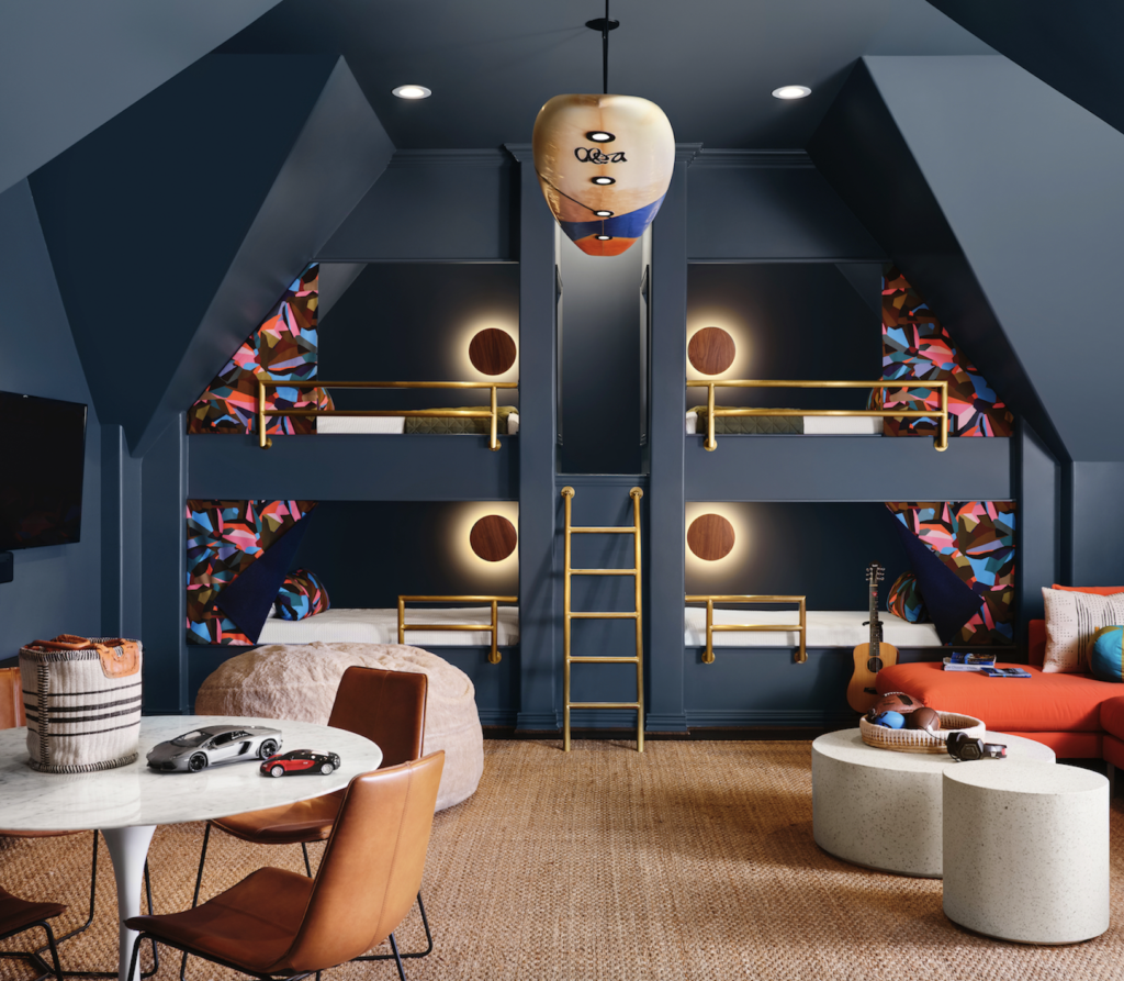 The former attic was converted into a game room for the couple’s children, with built-in bunk beds and a surfboard crafted into a hanging light fixture. Sconces by RBW, bed drapery by Kitty McCall, England. (Photo by Lisa Petrole)